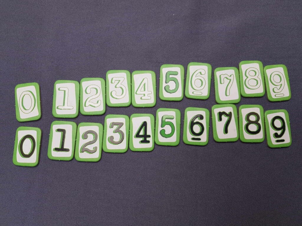 Break the code - tuiles de numéros de 0 à 9 blanches et noires (les 5 sont verts)